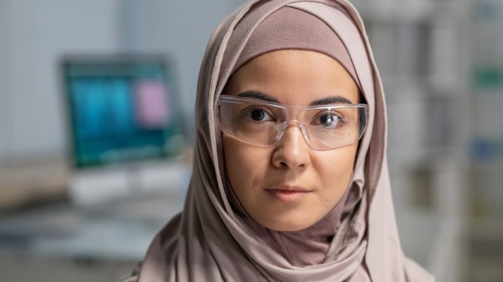 Face of young pretty Muslim female clinician in hijab and protective eyewear